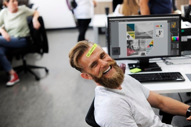 smiling man sitting in front of computer